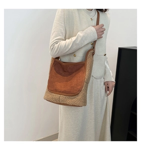 Détail du sac seau en daim et laine d'agneau avec bandoulière en cuir sur modèle