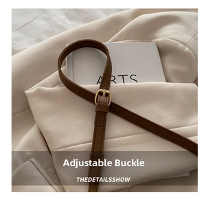Detail of brown litchi pattern leather strap with adjustable gold buckle and hardware