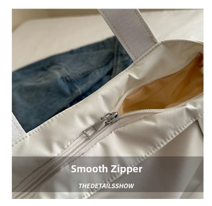 Close-up of smooth metal zipper detail on white large capacity casual canvas tote bag