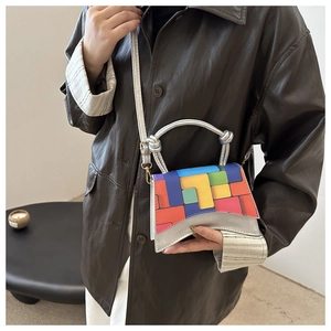 Detailed view of mini geometric color-block bag worn over a brown leather jacket