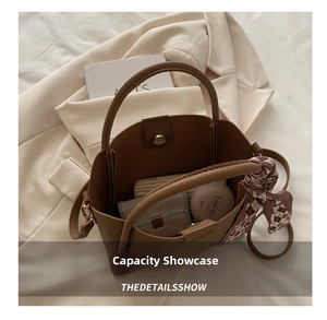 Detail view of brown pebbled leather bucket bag with items and a plaid scarf wrap