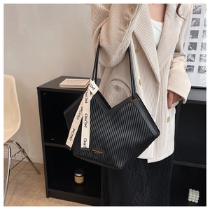 Detailed view of black pleated tote bag with V-shaped cut and branded fabric strap