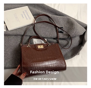 Detailed view of brown crocodile texture tote bag with gold metal lock and shoulder strap