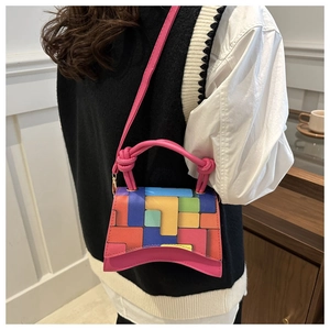 Detail of color-block mini handbag with curved base and geometric pattern on a model