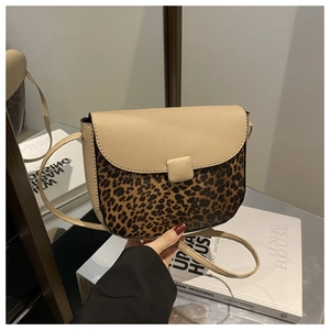 Detail of a chic leopard print crossbody bag with beige pebbled leather flap held by hand