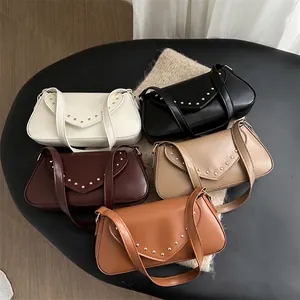 Retro baguette bags with metallic rivets in five colors on a textured display stand