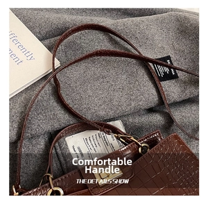 Detail view of dark brown croc-effect handbag with golden square lock and leather strap