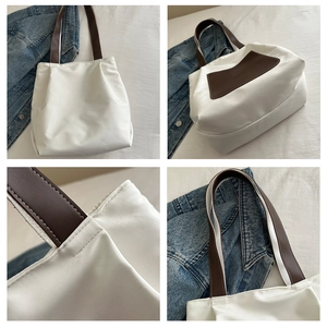 Detail view of white canvas tote bag featuring brown straps and high-quality stitching