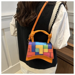 Detail of orange handbag with colorful geometric pattern and gold hardware on shoulder strap