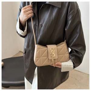 Detail of quilted beige shoulder bag with gold SS buckle and tassel on brown leather jacket