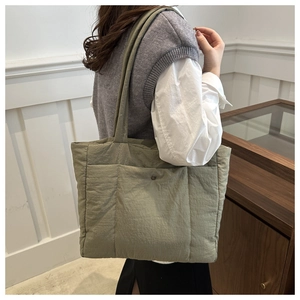 Close-up of light green quilted cotton tote bag with metal snap pocket on shoulder strap