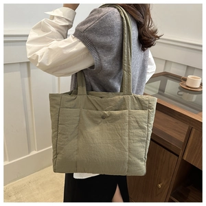 Detail of green quilted tote bag with front snap pocket and soft padded nylon texture