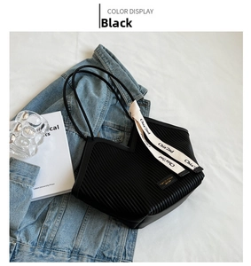 Detailed view of black pleated heart tote bag with ribbon on denim background