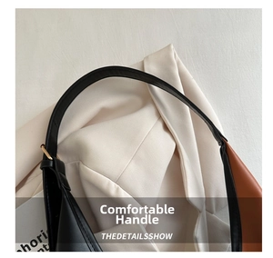Detail of bicolored shoulder bag showing black leather strap and metal buckle connection