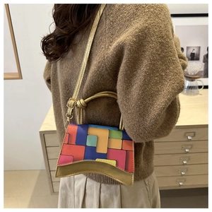 Detail of color-block geometric handbag with curved bottom and golden metal handle