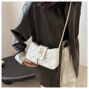 Detail of white quilted handbag with golden S-shaped logo and elegant tassel charm