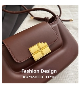 Detailed view of the dark brown leather saddle bag with square gold buckle and matte finish