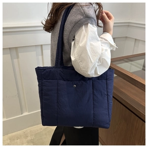 Detail of navy quilted space cotton tote bag with metal buckle and shoulder straps