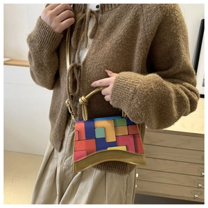 Detail view of hourglass-shaped colorful color-block handbag with gold metallic handle
