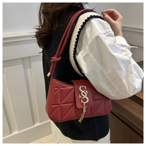 Detail of red quilted underarm bag with gold S-lock and metal tassel on a model