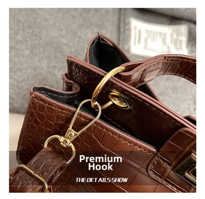 Close-up of gold metal hook and ring on brown crocodile texture tote bag strap