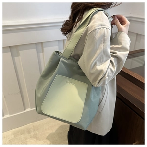 Detail of mint green nylon tote bag with leather pocket shown on model's shoulder
