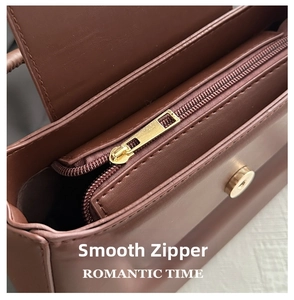 Detail of golden metal zipper and magnetic buckle on wine red baguette shoulder bag