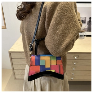 Detail view of colorful geometric patchwork shoulder bag with curved base on model