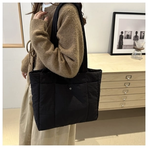 Close-up of black quilted nylon tote bag with square grid pattern and metal snap button