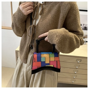 Detail of color-block geometric pattern on a stylish crossbody bag with curved base