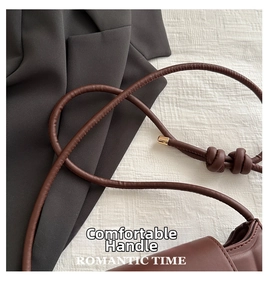 Detail of a brown leather bag with a unique knotted shoulder strap and gold hardware