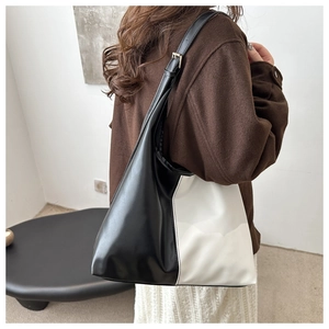 Detail of minimalist black and white PU leather tote bag with adjustable shoulder strap