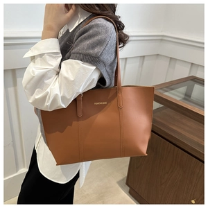 Vue latérale du grand sac cabas en cuir caramel porté par un mannequin chic