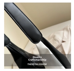 Detail showing high-quality leather stitching and shoulder strap connection on tote bag