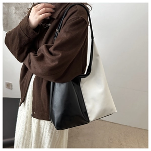 Detail of minimalist black and white color-block leather tote bag on shoulder