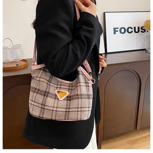 Close-up of pink and brown checkered hobo bag with gold triangular metal logo detail