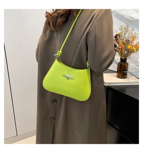 Bolso de hombro verde fluorescente con detalle de estrella plateada mostrado en modelo