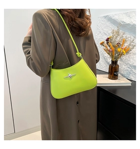 Bolso de hombro verde fluorescente sobre blazer marrón con hebilla de estrella plateada