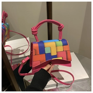 Detail of color-block geometric handbag with pink knotted handle and mirror reflection