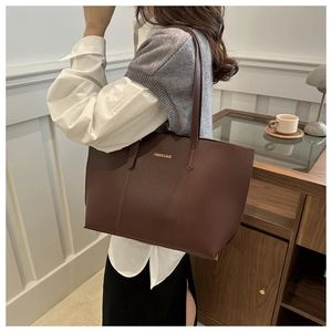 Détail du sac cabas en cuir marron foncé avec lettrage doré et fine bandoulière