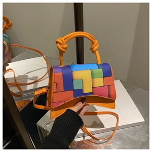 Detail of multi-color block handbag featuring a curved base and unique knotted handle