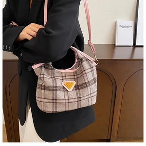 Detail of retro plaid shoulder bag featuring pink leather trim and yellow logo badge