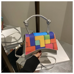 Detail view of silver handbag with colorful geometric puzzle pattern and metal handle