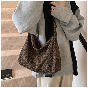 Detail of adjustable metal buckle and zipper closure on leopard print canvas bag