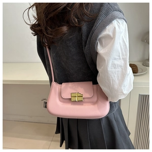 Detail shot of a pink leather saddle bag featuring a unique gold chocolate block buckle