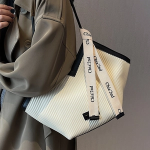 Vertical pleated white tote bag with black trim and decorative ribbon detail