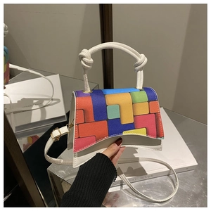 Detail of colorful block pattern on flap and twisted rope handle of the white shoulder bag