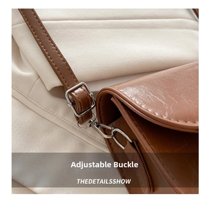 Macro detail of brown saddle bag showing the adjustable silver metal buckle and strap