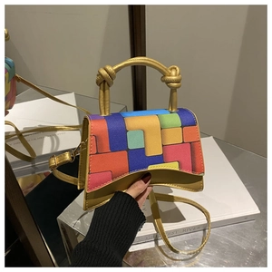 Detail of a gold crossbody bag with a colorful geometric patchwork flap and knot handle
