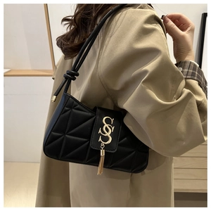 Close-up of black quilted shoulder bag with golden SS clasp and metal tassel detail